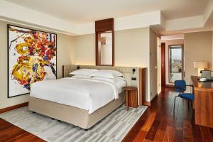 美因河畔法兰克福法兰克福朱美拉酒店的卧室配有一张床,墙上挂有绘画作品
