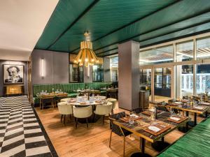多哈Rixos Gulf Hotel Doha的一间带桌椅和吊灯的餐厅