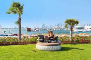 多哈Rixos Gulf Hotel Doha的坐在草地上豆袋椅上的女人