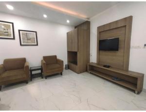安巴拉Hotel Sobti Plaza, Ambala, Haryana的客厅配有2把椅子和平面电视