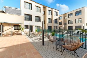 卡斯特尔德费尔斯Castell Beach Aparthotel的一个带椅子和游泳池的公寓庭院