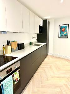 拉伊Rye Brand New Apartment的厨房铺有木地板,配有白色橱柜。