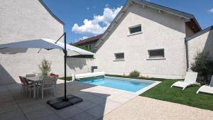 热夫雷尚贝尔坦La Maison de Caro的一个带桌子和遮阳伞的庭院和一个游泳池