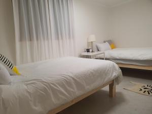 首尔Coco Stay的一间卧室配有两张带白色床单的床