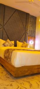 艾哈迈达巴德Hotel Primeland villa Gota的一间卧室配有一张大床和木制床头板