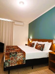 阿拉萨图巴里维埃拉酒店的一间卧室设有一张床和蓝色的墙壁