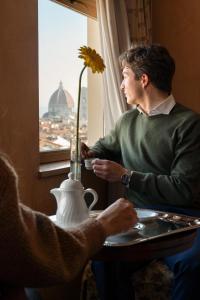 佛罗伦萨亚德里亚海大酒店的坐在桌子上看窗外的人