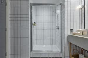 伦敦One Hundred Shoreditch的浴室铺有白色瓷砖,设有淋浴。