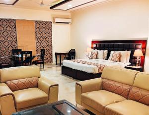 古尔冈When In Gurgaon - ARTEMIS HOSPITAL 1 Min Walk, FORTIS & MEDANTA 4 Mins Drive的酒店客房配有一张床、一张沙发和椅子。