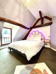罗莫朗坦Le Nid Arrivé autonome clim wifi linge inclus的一间卧室配有白色床和紫色照明