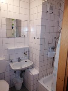 Dettingen unter TeckZimmervermietung Gasthof Lamm, Zugang selbstständig über Schlüsseltresor的白色瓷砖浴室设有水槽和浴缸