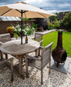 邓弗姆林Linburn Cottage Dunfermline near Edinburgh的一张桌子、一把遮阳伞、两把椅子和一瓶啤酒