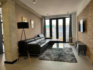 格拉纳达Elegante piso reformado a 1km del centro的客厅配有黑色真皮沙发和砖墙