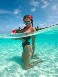 汉纳梅杜岛BY THE SHADE的水里一个比基尼的女人,在水里拿着冲浪板