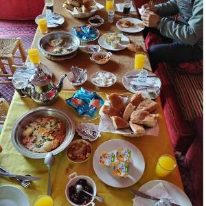 梅尔祖卡Hostel la palmeraie merzouga的餐桌上放有食物和面包的盘子
