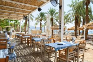埃拉特Royal Beach Eilat by Isrotel Exclusive的海滩上的餐厅,配有桌椅