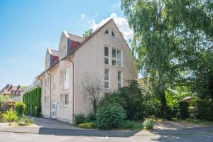 卡塞尔CASSEL LOFTS - Idyllische Maisonette-Wohnungen nähe Bergpark Wilhelmshöhe的一座大白色房子,有树木和灌木