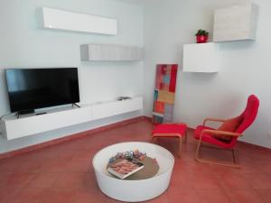 锡耶纳Casa Arcobaleno的一间带电视和红色椅子的客厅