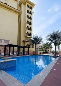 迪拜Veluxa - Fantastic 1 Bed - in Jumeirah Golf Estate!的棕榈树建筑前的游泳池