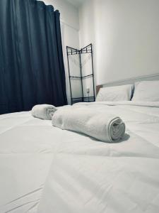 东贡岸Comfy suites的卧室内配有两张带毛巾的白色床。