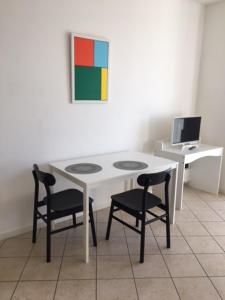 帕多瓦flat in Padova center的一张带两把椅子的白色桌子和一张带电脑的桌子