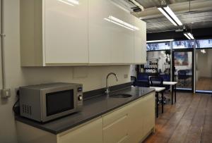 伦敦Cosmos capsule coworking London的厨房配有白色橱柜和台面上的微波炉