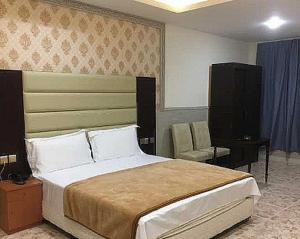 拉斯阿尔卡麦OYO Al Taj Rest House的一间卧室配有一张大床和一把椅子
