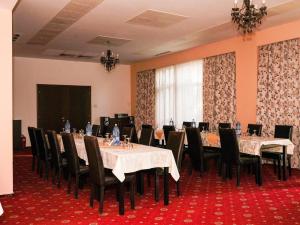 布加勒斯特HOTEL CRISS的一间会议室,配有长桌子和椅子以及屏幕