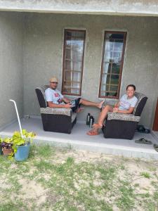 马翁Partulaka Rest Inn的坐在房子前面椅子上的两个人