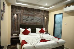 贾姆谢德布尔Hotel Trax International的一间卧室配有一张带红色枕头的大床