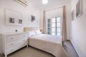 尼科西亚Pageant Homes的白色的卧室设有白色的床和窗户。