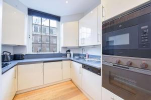 伦敦2 Bedroom Apartment- Mayfair (4)的厨房配有白色橱柜和黑色用具