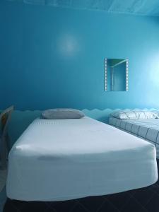 萨利诺波利斯Apartamentos no Farol Velho的蓝色背景的客房内的两张床