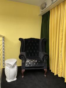 伦敦Victoria Park Apartment的一张黑色沙发,坐在带窗帘的房间