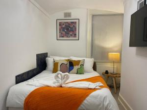伦敦Central Point apartment的一间卧室配有一张带橙色毯子的床