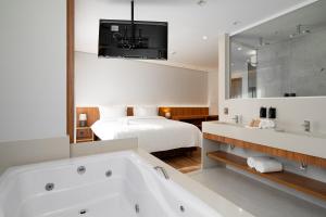 佩尼多Vert Hotel Penedo的带浴缸和床的浴室
