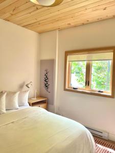 Marion BridgeModern waterfront cottage +hot tub的卧室配有白色的床和窗户。