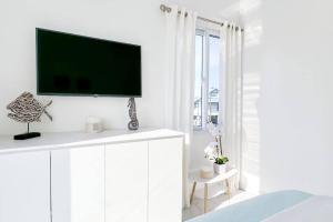 特拉Atlantis Villages Poseidon的白色卧室,白色墙壁上配有平面电视
