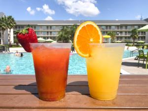 奥兰多Avanti International Resort的坐在泳池旁的桌子上喝两杯饮料
