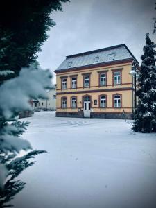 博尔纳Hotel zur Schlossmühle的前面有雪的大建筑