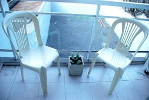 布宜诺斯艾利斯Departamento en Flores, Ciudad de Buenos Aires的门廊上两把白色椅子和盆栽植物