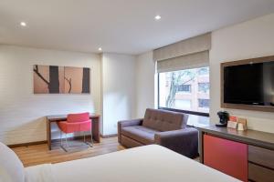 波哥大84 DC Bogotá的酒店客房配有床椅和电视。