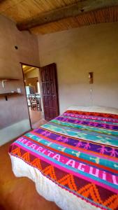 蒂尔卡拉MAMAICUNA CABAÑA的一间卧室配有一张带彩色毯子的床