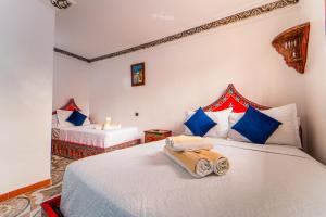 舍夫沙万Hotel Chefchaouen的一间卧室配有两张带蓝色和红色枕头的床