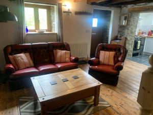 阿伯里斯特威斯Tanyresgair Cottages的客厅配有两张真皮沙发和一张茶几