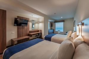 卡门城La Venta Inn Ciudad del Carmen的酒店客房设有两张床和一台平面电视。