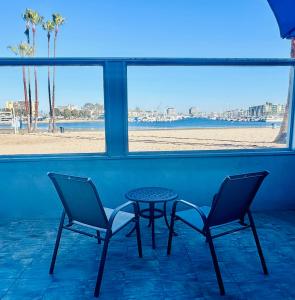 洛杉矶Foghorn Harbor Inn的海滩前的两把椅子和一张桌子
