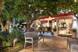 尼斯尼斯布莱斯花园贝斯韦斯特优质酒店的坐在商店前树下的长凳