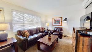 摩押Downtown Cozy Home Base - Purple Sage 3的客厅配有真皮沙发和桌子