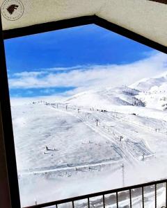 Popova ShapkaVilla Winterfell Popova Shapka的从雪覆盖的山窗上可欣赏到风景